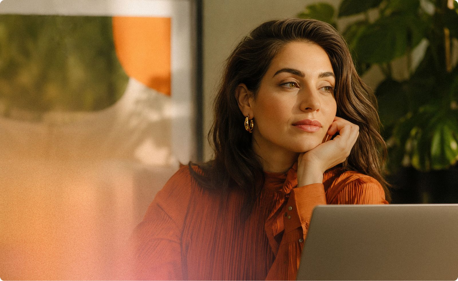 Writer sitting in warm light with a laptop, focused and reflective.